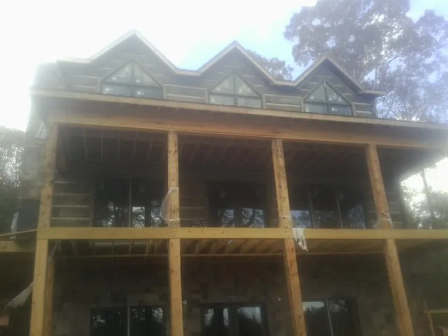 Dormers and porch framing on a large log home under construction — Roof Coating work by our crew in Rockford